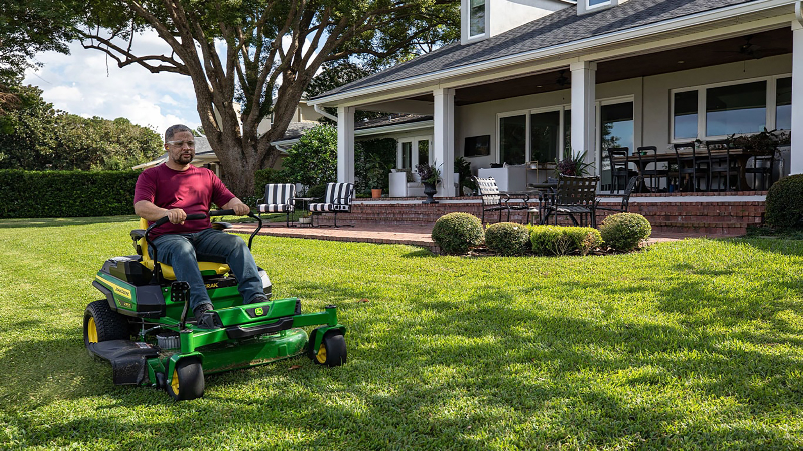 Man riding an electric John Deere mower.