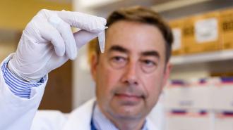 a scientist looking at a small test tube