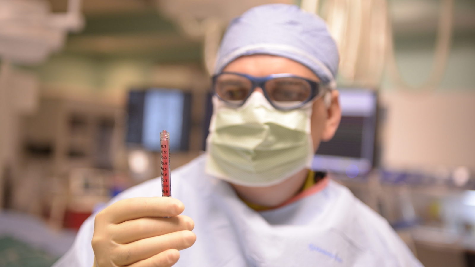 a doctor holding a syringe full of a red liquid