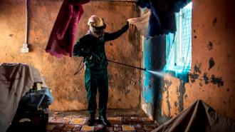 worker spraying pesticide inside a home